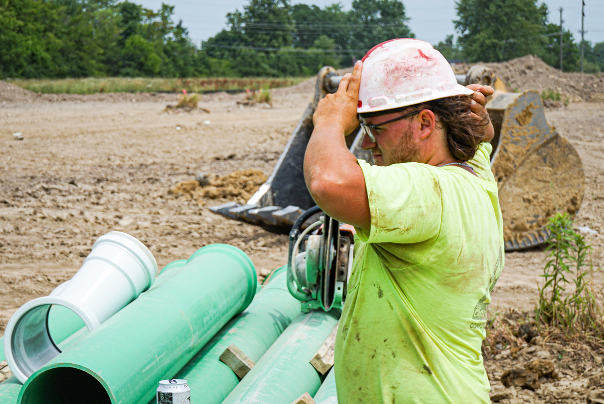 construction worker putting on white hard hat on site